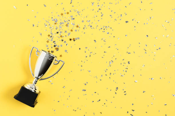 istock Winner or champion silver trophy cup on yellow background top view. 1291825219