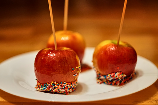 Christmas caramelized apples on a plate. Delicious red candy apples topped with colorful sprinkles