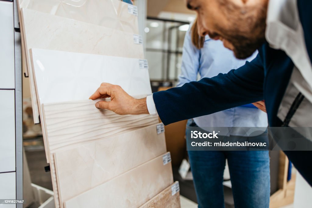 Bathroom tiles and utensils shopping Elegant middle age businessman choosing ceramic tiles and utensils for his home bathroom and female seller helps him to make right decision Tile Stock Photo