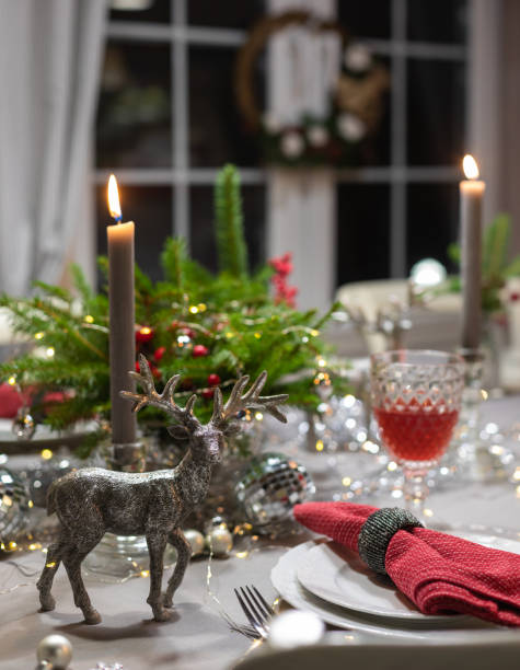 istock Table served for Christmas dinner, festive setting with decorations, burning candles and fir-tree branches 1291830845
