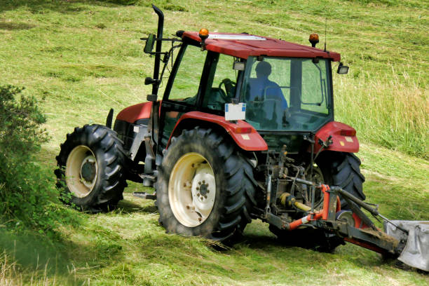 Grass Cutting Tractor cutting grass in a field prior to drying and baling tractor mowing stock pictures, royalty-free photos & images