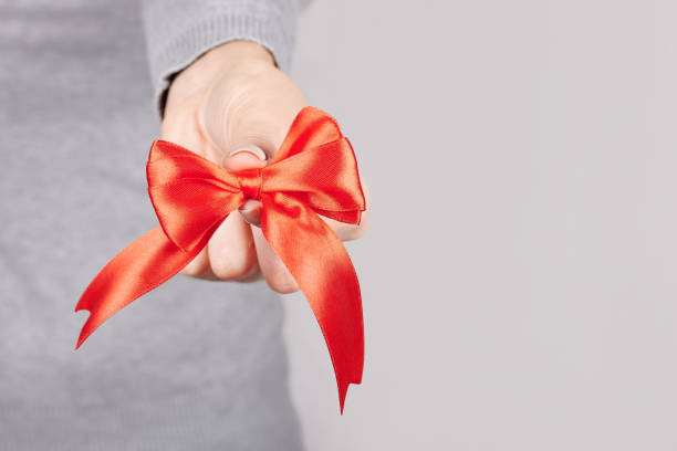 istock Hand with red ribbon on grey background. 1291835555