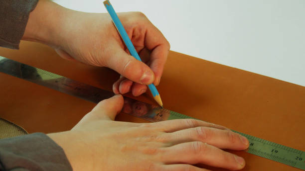 istock A shoemaker makes a pattern for boots made of genuine leather. Use a pencil and ruler to draw a straight line for the cut 1291836359