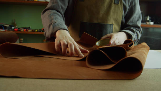 istock A professional Tanner corrects defects on a roll of genuine leather with a special wax. The process of creating a hand made product 1291836695