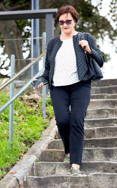istock Mature woman walking down on steps, background with copy space 1291837440