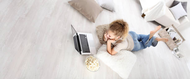 young woman lying on the floor at the computer with popcorn in living room, top view image and stay at home concept young woman lying on the floor at the computer with popcorn in living room, top view image and stay at home concept woman lying on the floor isolated stock pictures, royalty-free photos & images