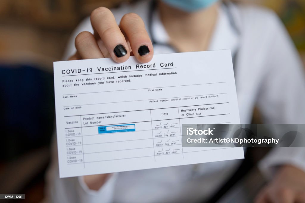 Doctor holding COVID-19 Vaccination Record Card. Close up of unrecognizable female doctor holding a COVID-19 Vaccination record card. Immunization Certificate Stock Photo