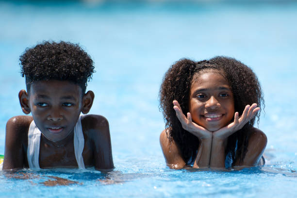 african girls lay down in swimming pool. Concept children self playing in summer day at outdoor activity sport recreation. african girls lay down in swimming pool. Concept children self playing in summer day at outdoor activity sport recreation. swimwear bikini top bikini bikini bottom stock pictures, royalty-free photos & images