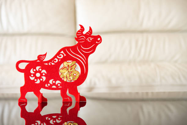 an ox mascot as symbol of Chinese New Year of the Ox in front of a sofa the Chinese means good luck an ox mascot as symbol of Chinese New Year of the Ox in front of a sofa the Chinese means good luck chinese zodiac sign photos stock pictures, royalty-free photos & images