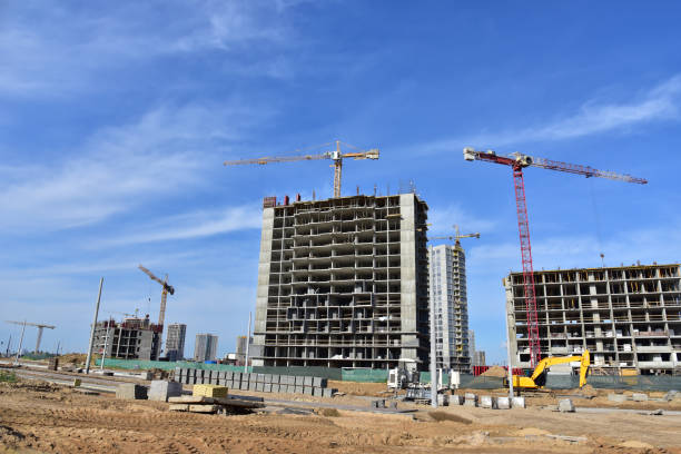 istock Tower cranes in action on blue sky background. Excavator dig ground for foundation pit at construction site 1291851552