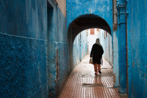 rabat, marocco: donna in vicolo blu a medina - women rear view one person arch foto e immagini stock
