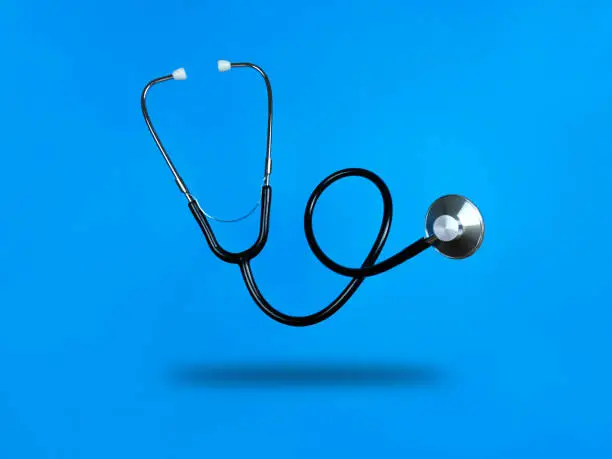 Levitating stethoscope on a blue background and shadow under it. Stock photo.