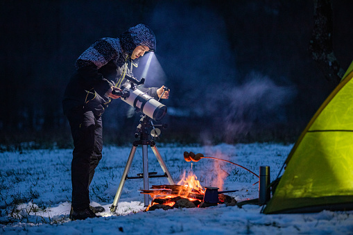 Astronomer Adjusting and Preparing Telescope By His Camp in Winter.