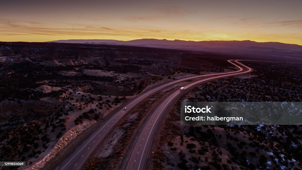 Truck and Car on I-70 in San Rafael Swell After Sunset - Aerial Aerial shot of Interstate 70 cutting through the San Rafael Swell on the Colorado Plateau in southern Utah at sunset. A light dusting of snow is visible. Highway Stock Photo