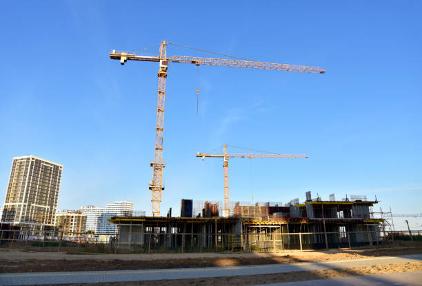 istock Tower cranes working at construction site on blue sky background 1291856102