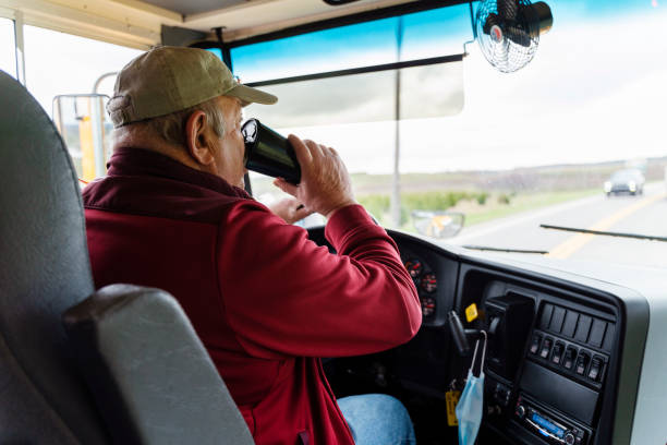 istock Senior man, the bus driver, driving a school bus and drinking a coffee. 1291873725