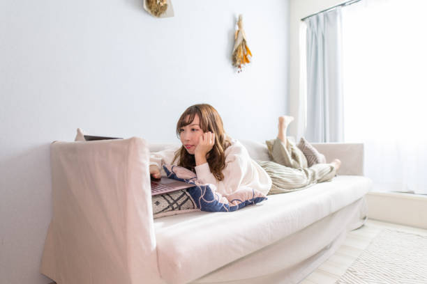 istock Young woman lying down on sofa and working at home 1291878615