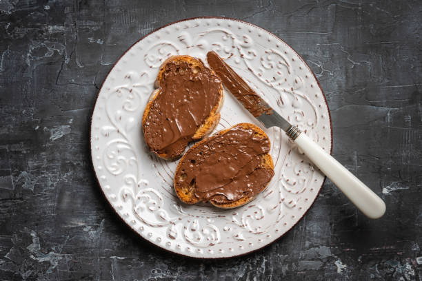 istock Slice of homemade bread with chocolate cream on the kitchen table for breakfast. Selective focus. Shallow depth of field. 1291881378