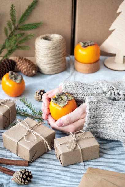 istock Natural Christmas background, craft gift boxes, cones, Christmas tree on the table, close-up, retro style. A girl in a sweater is packing gifts. The happy atmosphere of the holiday 1291883140
