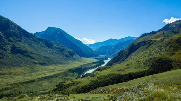 istock Green valley landscape and small river with mountains on background 1291884830