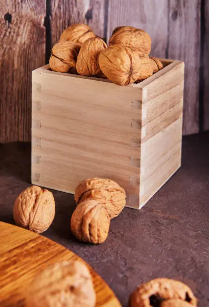 Photo of Walnuts in a wooden box, whole and finely chopped, next to the filling and shells on a wooden background