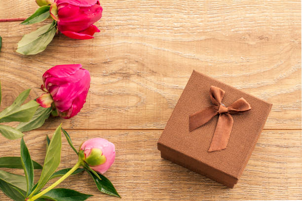 istock Gift box on wooden boards with peony flowers. 1291886549