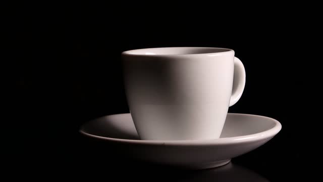 Ceramic coffee cup rotates on a black background. Cup and saucer. Ceramic tableware. Coffee house. Cafe. Kitchenware. Hot drink. Black background. Rotation in a circle. Video.