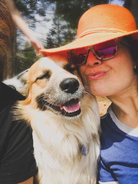 Cute woman in big orange straw hat with her smiling dog on an adventure . stock photo