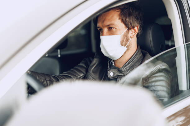 istock Young man driving car in medical mask 1291895146