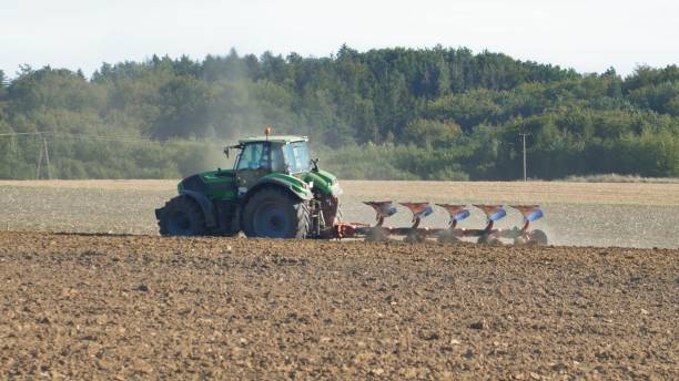 istock Farmer Ploughing Soil using Tractor with Mouldboard Plough on Sunny Day 1291896467