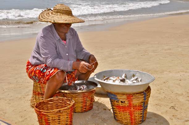 istock Woman Cleaning Fish While Sitting On Beach 1291900060