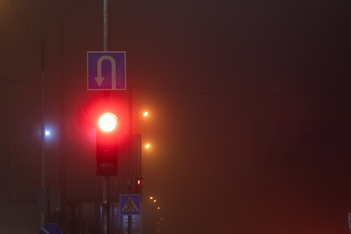 red traffic light in night city fog copy space