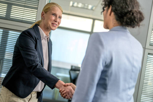 istock Smiling businesswoman shaking hands with female client 1291905637