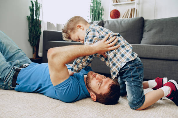 istock Father and son playing together on carpet at home 1291907346