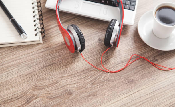 istock Red headphones, coffee, computer keyboard, pen and notepad on the wooden desk. 1291908124