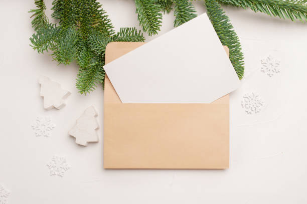 istock Christmas greeting card with envelope on wooden white background with fir tree branches and happy new year decorations. Top view copyspace 1291908381
