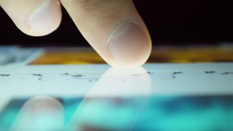 Close up Macro Man Browsing Tablet Computer With Finger. Person Using Smartphone, Browsing through Pictures on Social Network Wall. Close Up Finger Scrolling Social Media App Feed.