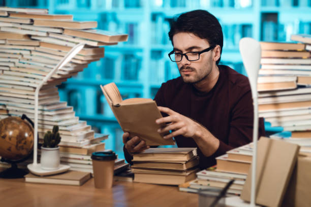istock White guy surrounded by books in library. Student is reading book. 1291909517