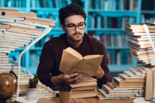 istock White guy surrounded by books in library. Student is reading book. 1291909590