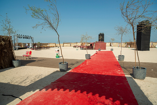 Public recreation area in Dubai. Place for various events. Tent and red carpet on sand.