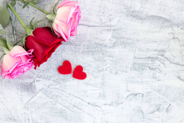 istock Two red hearts and three rose on a stone white background. Romantic gift for Valentine's day. Love. Soft focus. Copy space. 1291914124