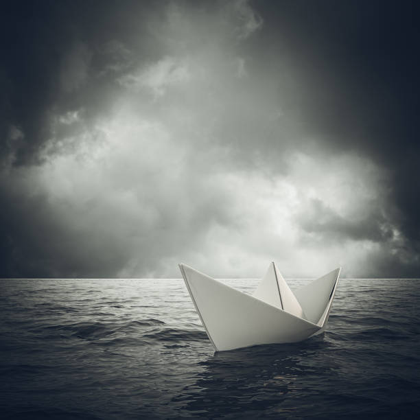 istock paper boat sails alone in a vast ocean. 1291914477