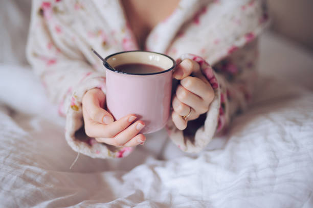 istock Female hands holding a cup with tea in bed 1291915036