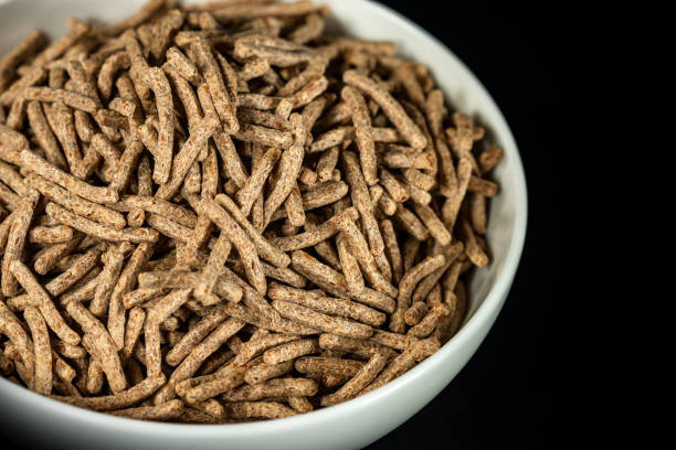 bâtons de son dans une tasse blanche d’isolement sur le fond noir - bran flakes photos et images de collection