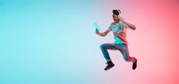 Young caucasian man's portrait on gradient blue-pink studio background in neon light Music, drive. Young caucasian man's jumping on gradient blue-pink studio background in neon light. Concept of youth, human emotions, facial expression, sales, ad. Half length, copyspace. Flyer neon portrait boy stock pictures, royalty-free photos & images