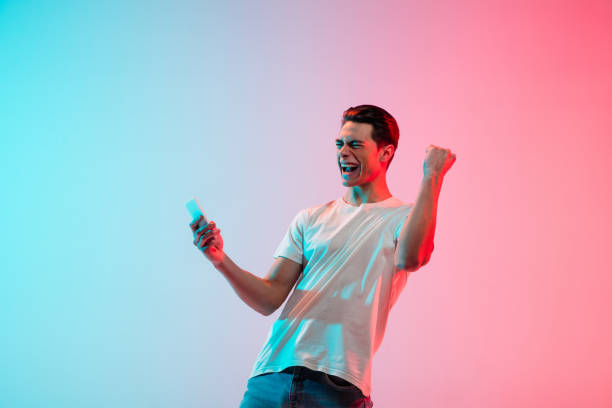 istock Young caucasian man's portrait on gradient blue-pink studio background in neon light 1291915550