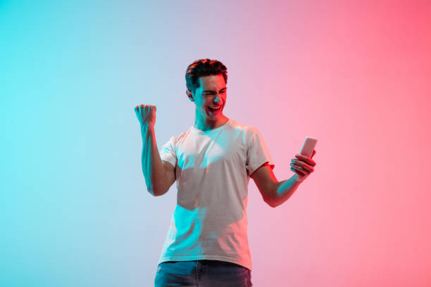 istock Young caucasian man's portrait on gradient blue-pink studio background in neon light 1291916060