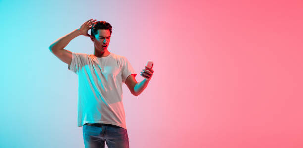 istock Young caucasian man's portrait on gradient blue-pink studio background in neon light 1291916067