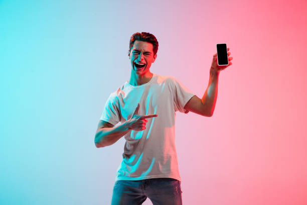 istock Young caucasian man's portrait on gradient blue-pink studio background in neon light 1291916079