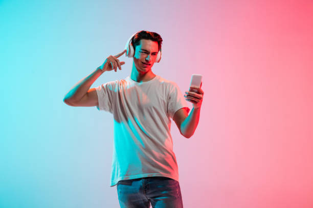istock Young caucasian man's portrait on gradient blue-pink studio background in neon light 1291916095